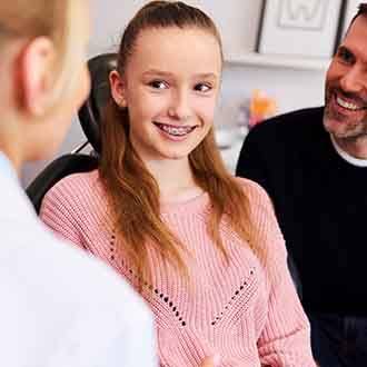 Smiling patient talking to orthodontist with parent