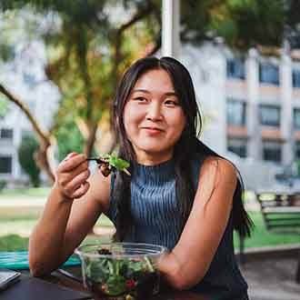 Woman smiling while eating salad outside